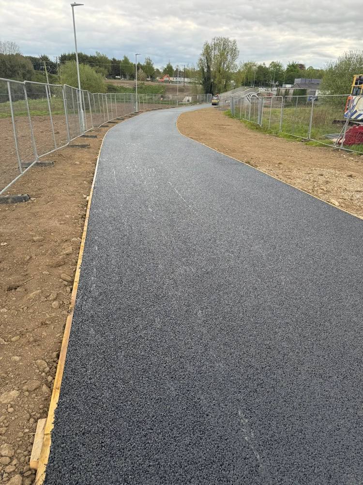 A newly surfaced curved footpath and access road with a clean edge against fresh ground.