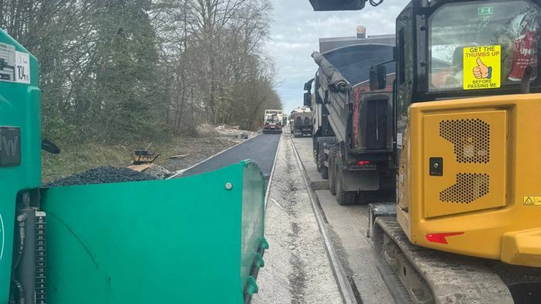 A tipper feeding the paver on the Royal Canal bank, with an excavator working alongside.
