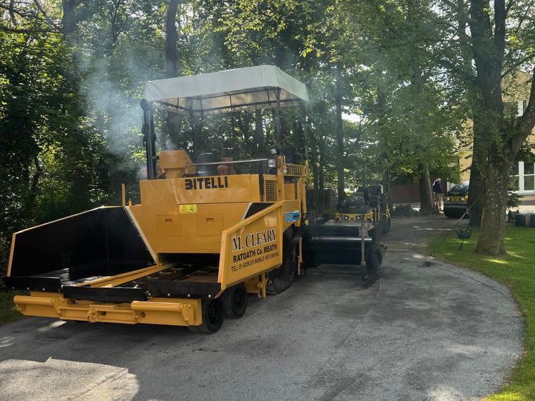 The yellow Bitelli paver laying a private driveway under mature trees.