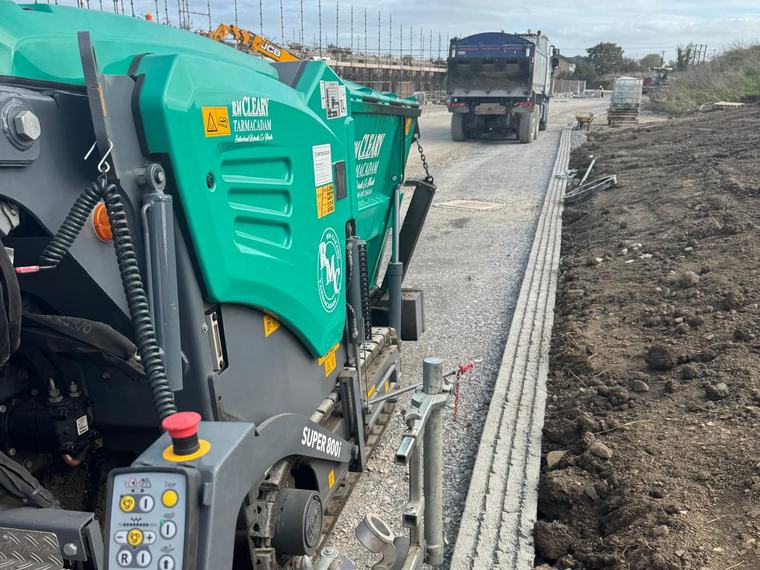 The green Vögele SUPER 800i paver working to a newly set kerb line on an estate road.