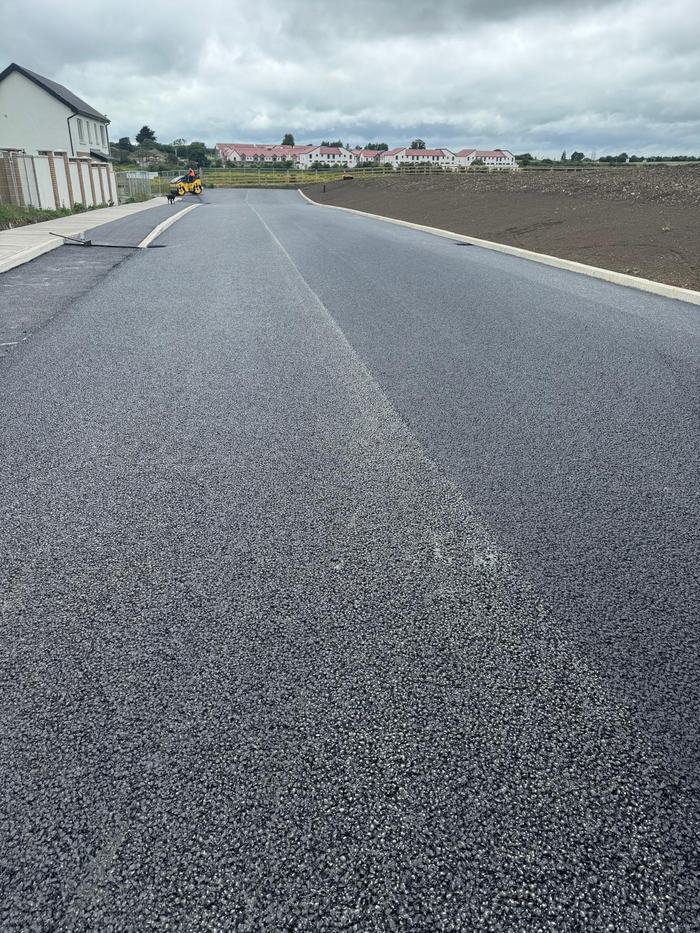 The completed road running away between the houses with the roller finishing behind.