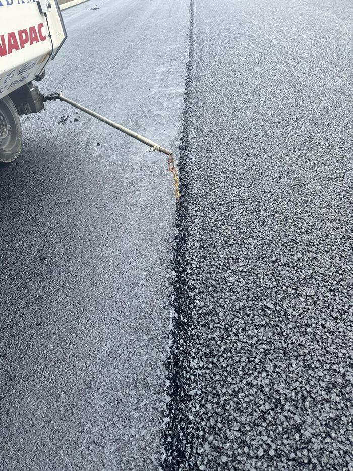 Close detail of the longitudinal joint between the completed run and the fresh mat.