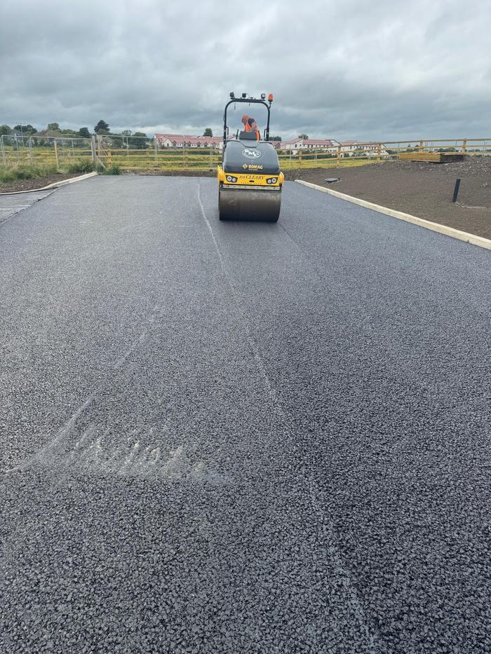 An RM Cleary BOMAG roller compacting the new surface on the wide section of the road.
