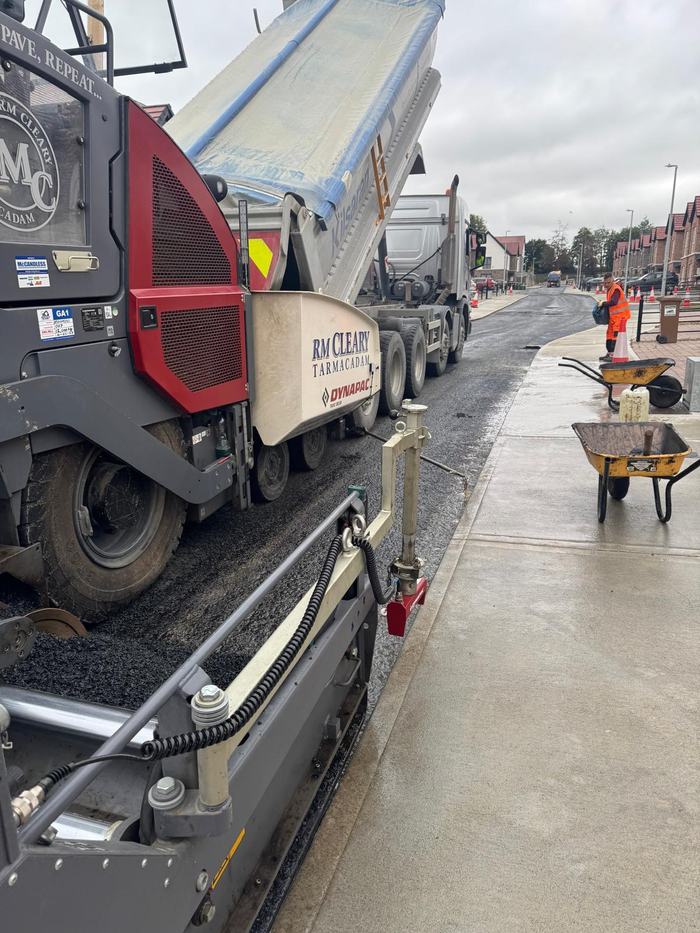 A tipper discharging into the RM Cleary paver alongside the finished footpath.