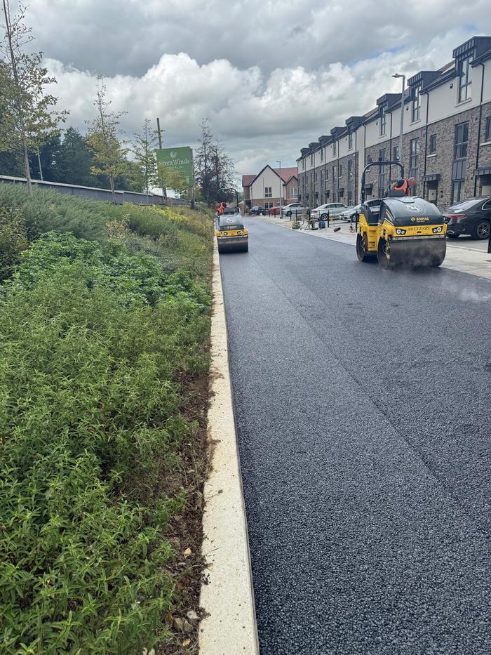 Two RM Cleary rollers compacting the new surface along a completed estate street, steam rising off the mat.