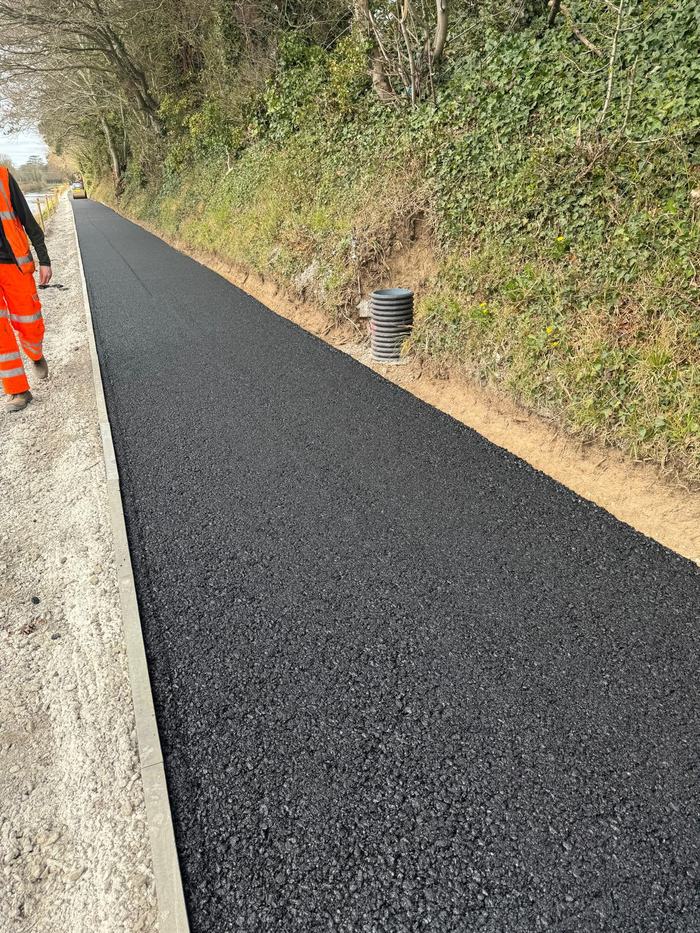 The completed greenway surface with a clean kerbed edge, looking along the finished run.