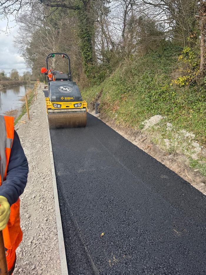 An RM Cleary roller compacting the new greenway surface with the canal on one side and a cut bank on the other.