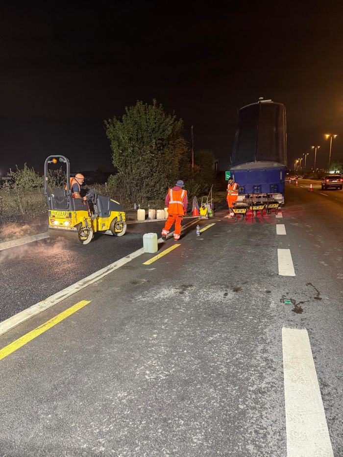 The roller and a tipper on the closed lane, the crew filling barrows off the back of the lorry.