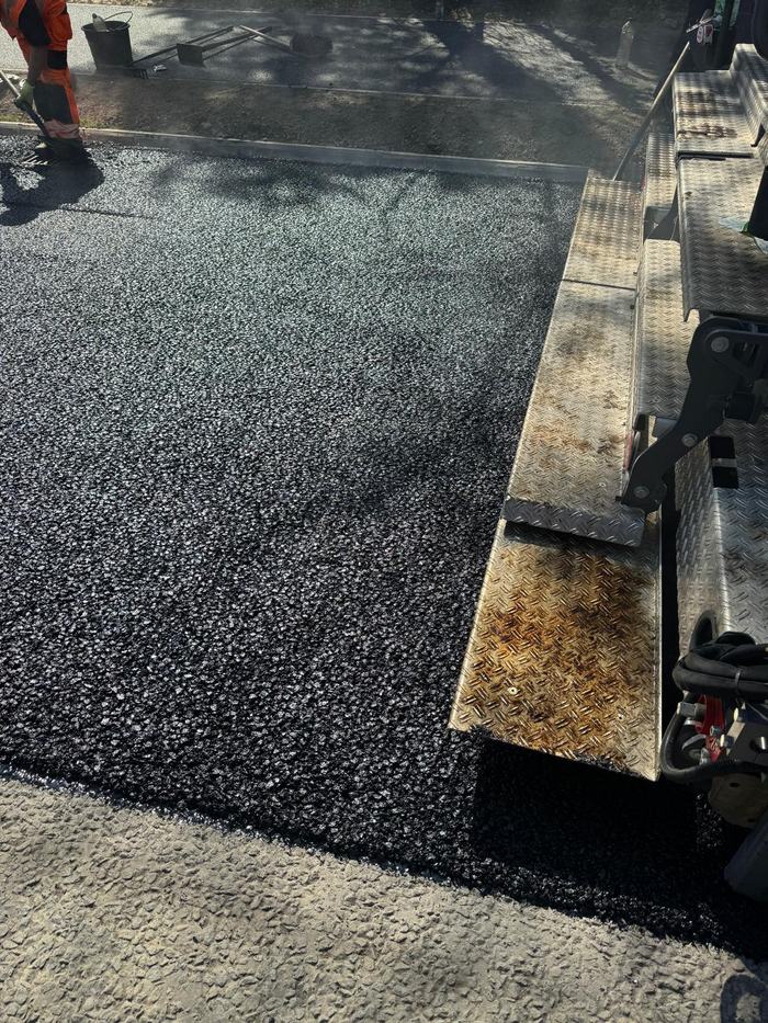 Close detail of the fresh mat coming off the screed, still steaming.