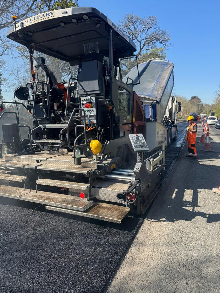The back of the paver with a crew member working the edge against the old surface.